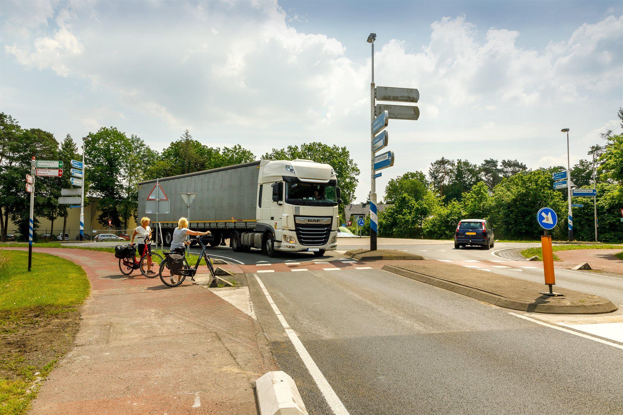 Vrachtwagen op de rotonde met wachtende fietsers